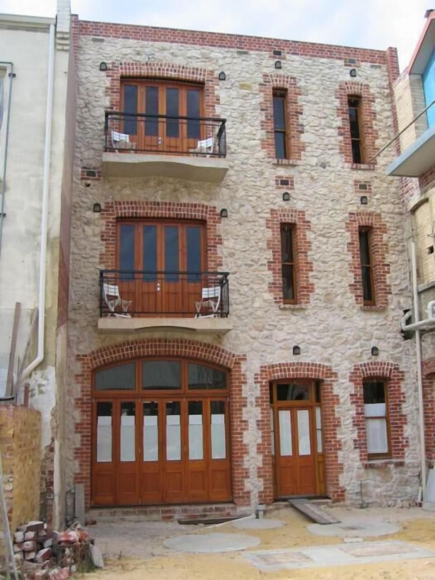 A multi-story building with a stone facade, large wooden doors, and balconies.