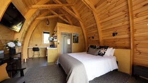 A cozy, wooden interior with a large bed, a desk, and a dining area. - Benger Garden Cafe & Chalets (Ettrick)