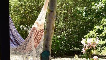 A hammock tied to a tree, a wooden deck, and a garden with various plants.