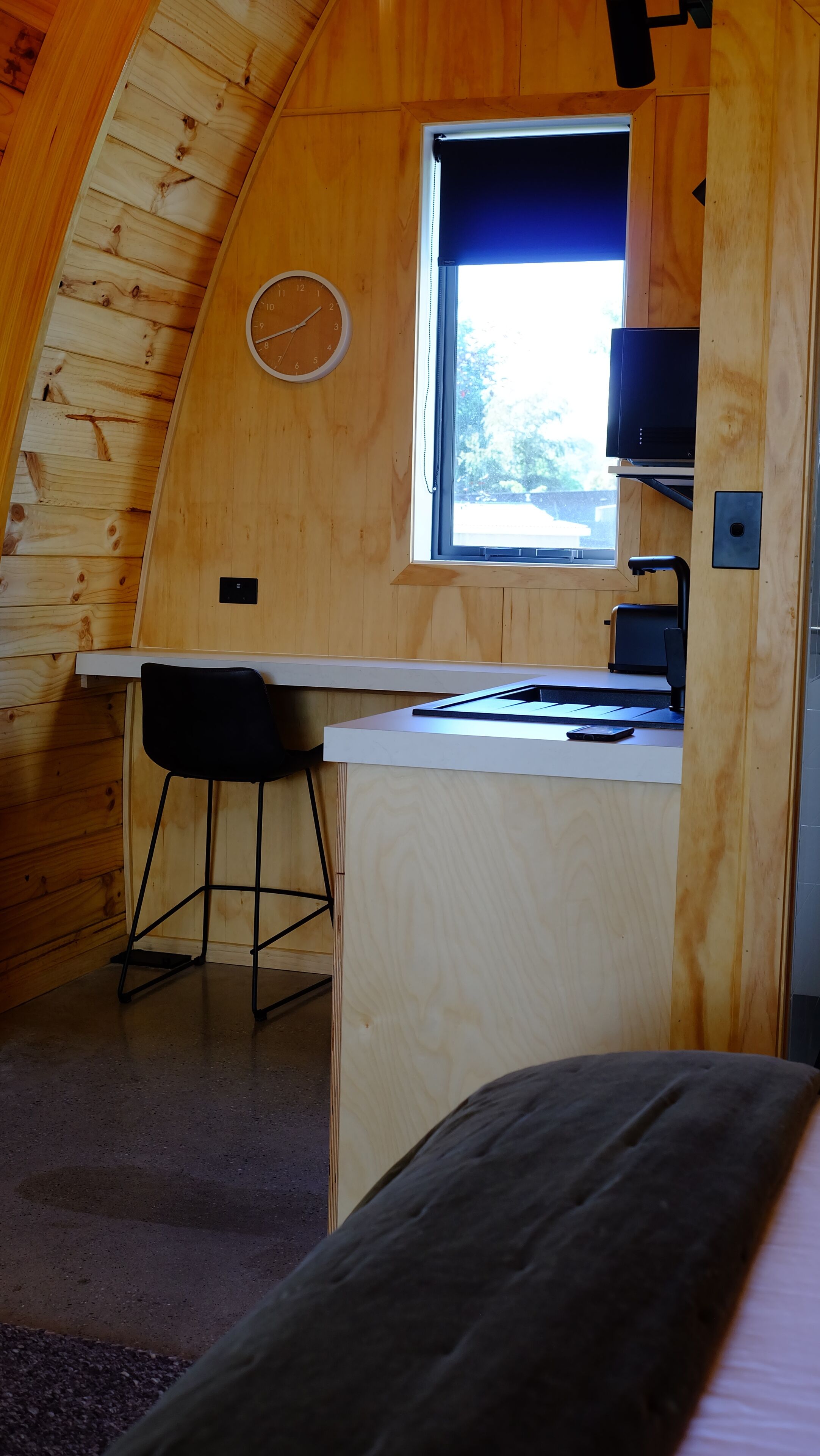 A compact wooden room with a desk, a chair, a bed, and a window.