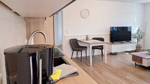A modern kitchen with a built-in stove, a dining area with a table and chairs, and a TV on a stand. - Idyllic vacation home "Björn", Büsum (6km), terrace, parking lot, secluded location (Reinsbüttel)