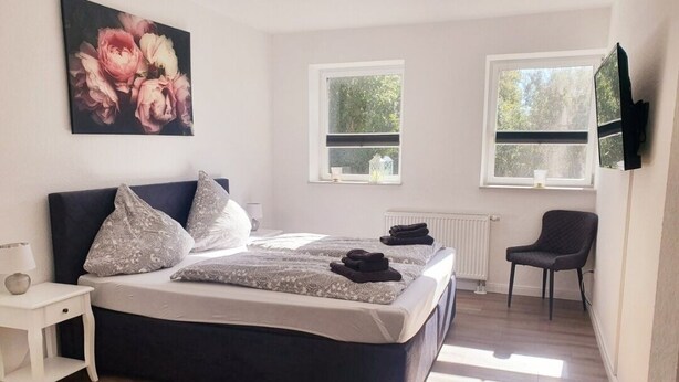 A bedroom with a large bed, a bedside table, a chair, and a TV mounted on the wall. - Idyllic vacation home "Björn", Büsum (6km), terrace, parking lot, secluded location (Reinsbüttel)