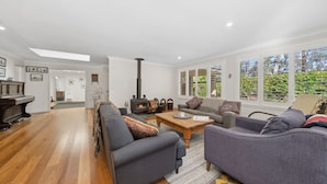A spacious living room with a fireplace, a piano, and large windows with blinds. - Senang in Blackheath (Blackheath)