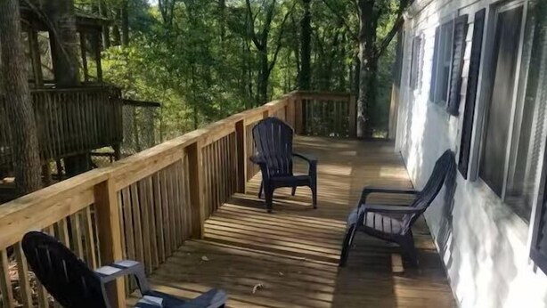 Una terraza de madera con dos sillas Adirondack y una barandilla.