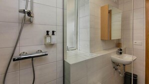 A modern bathroom with a shower, a sink, and a mirror. - Thomsen Residence Suites (Reykjavik)