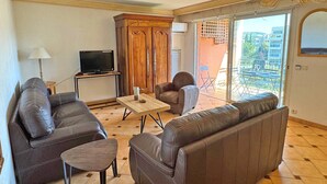A living room with leather sofas, a coffee table, and a TV. - Apartment for 6 people - Swimming pool - Air conditioning - WiFi - Sainte Maxime (STE MAXIME)