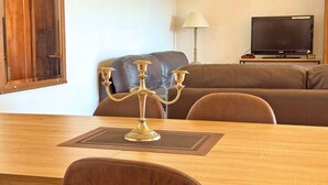 A dining table with a placemat, a candelabra, a sofa, a television, and a lamp in a living room setting. - Apartment for 6 people - Swimming pool - Air conditioning - WiFi - Sainte Maxime (STE MAXIME)