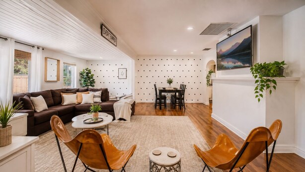 A modern living room with a sofa, two leather chairs, a coffee table, and a dining area with a table and chairs. - Stay Near Beach, Sleep 12, Grill, Pool Table, Family & Event Open (West Palm Beach)