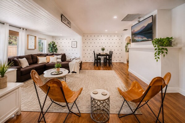 Una sala de estar moderna con un sofá, dos sillones de cuero, una mesa de centro y un comedor con mesa y sillas.