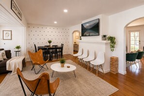 Un salon comprenant une cheminée, un coin repas et un espace détente avec des fauteuils et un canapé.