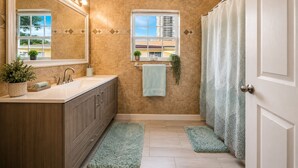 A bathroom with a vanity, a mirror, a window, a shower curtain, and a small plant. - Stay Near Beach, Sleep 12, Grill, Pool Table, Family & Event Open (West Palm Beach)