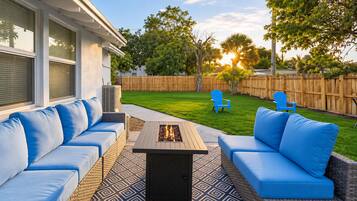 Eine Terrassengruppe im Freien mit einem Feuerkorb, zwei blauen Sofas und zwei blauen Sesseln.