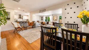 A modern kitchen with white cabinets, a dining area with a wooden table and chairs, and a living room with a sofa and coffee table. - Stay Near Beach, Sleep 12, Grill, Pool Table, Family & Event Open (West Palm Beach)