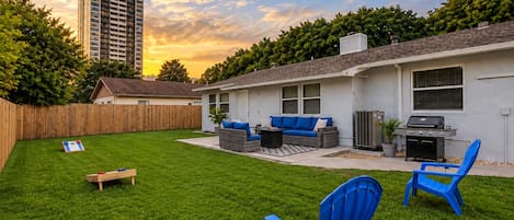 A backyard with a patio, outdoor furniture, and a grill.