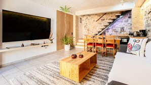 Un saló amb televisió, taula de centre de fusta, sofà i una escala que porta a una cuina.