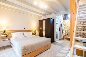 A bedroom with a bed, bedside lamps, a wardrobe, and a staircase leading to an upper level. - Limni Stone Apartments (Mantoudi-Limni-Agia Anna)