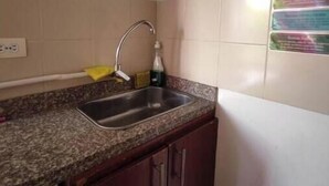 A kitchen with a granite countertop, stainless steel sink, wooden cabinets, and a white refrigerator. - Colorful awakening! apartment-studio (Cali)