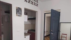 A hallway with a kitchen area, a toilet, and a door leading to another room. - Colorful awakening! apartment-studio (Cali)