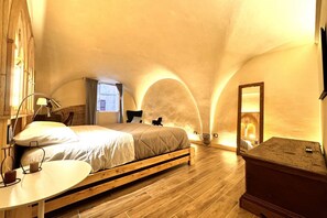 A bedroom with a wooden bed, a bedside table, a mirror, and a small window. - Stalloregis 19 - near the Duomo (Siena)