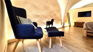 A modern interior with a high arched ceiling, a blue upholstered chair with a patterned pillow, a small wooden table, and a decorative horse statue. - Stalloregis 19 - near the Duomo (Siena)