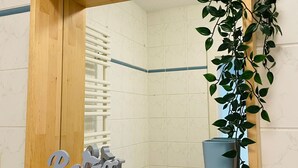 A bathroom with a wooden-framed mirror, a potted plant, and a decorative sign.