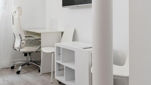A modern office space with a white desk, chair, and shelving unit.