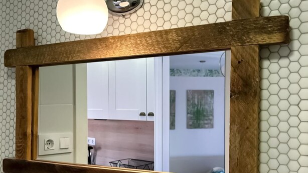 A mirror with a wooden frame mounted on a wall with hexagonal tiles. - Sol Studio III - Apartment in the City Center with Balcony (Madrid)