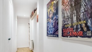 A hallway with white walls and wooden flooring, featuring two movie posters. - La Latina Life - 2-Bedroom Apartment with Balcony (Madrid)