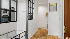 A hallway with a glass table, a door with a key lock, and a lamp. - La Latina Life - 2-Bedroom Apartment with Balcony (Madrid)
