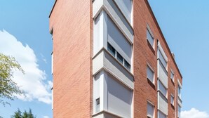 Un edificio de varios pisos con fachada de ladrillo rojo y marcos de ventanas blancos.
