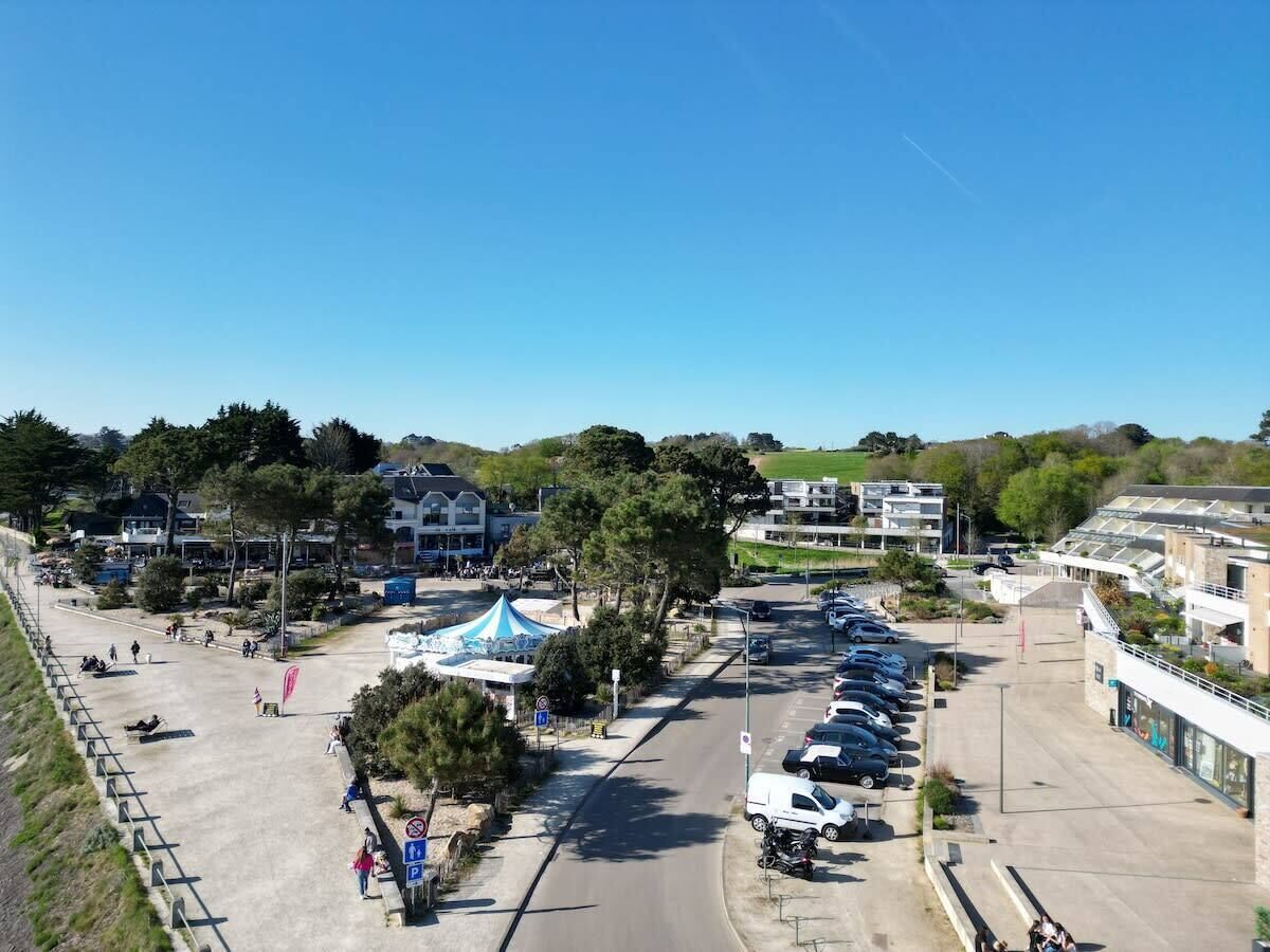 A parking lot with multiple cars, a tent, and buildings in the background.