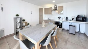 Eine moderne Küche mit Essbereich, ausgestattet mit einem großen Tisch, Stühlen und einem eingebauten Backofen.