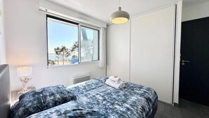 Ein Schlafzimmer mit Bett, Fenster, Tür und Nachttisch mit Lampe.