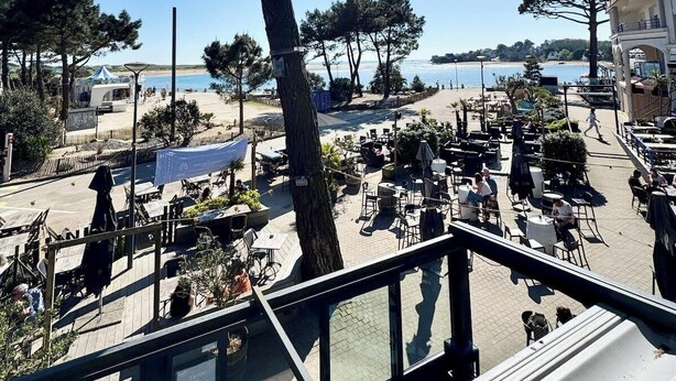 Eine Terrasse mit Sitzgelegenheit im Freien mit Blick auf einen Strand und das Meer, inklusive freier Sicht auf den Horizont.