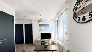 Ein modernes Wohnzimmer mit einer Couch, einem Couchtisch, einem Fernseher und einer großen Wanduhr.