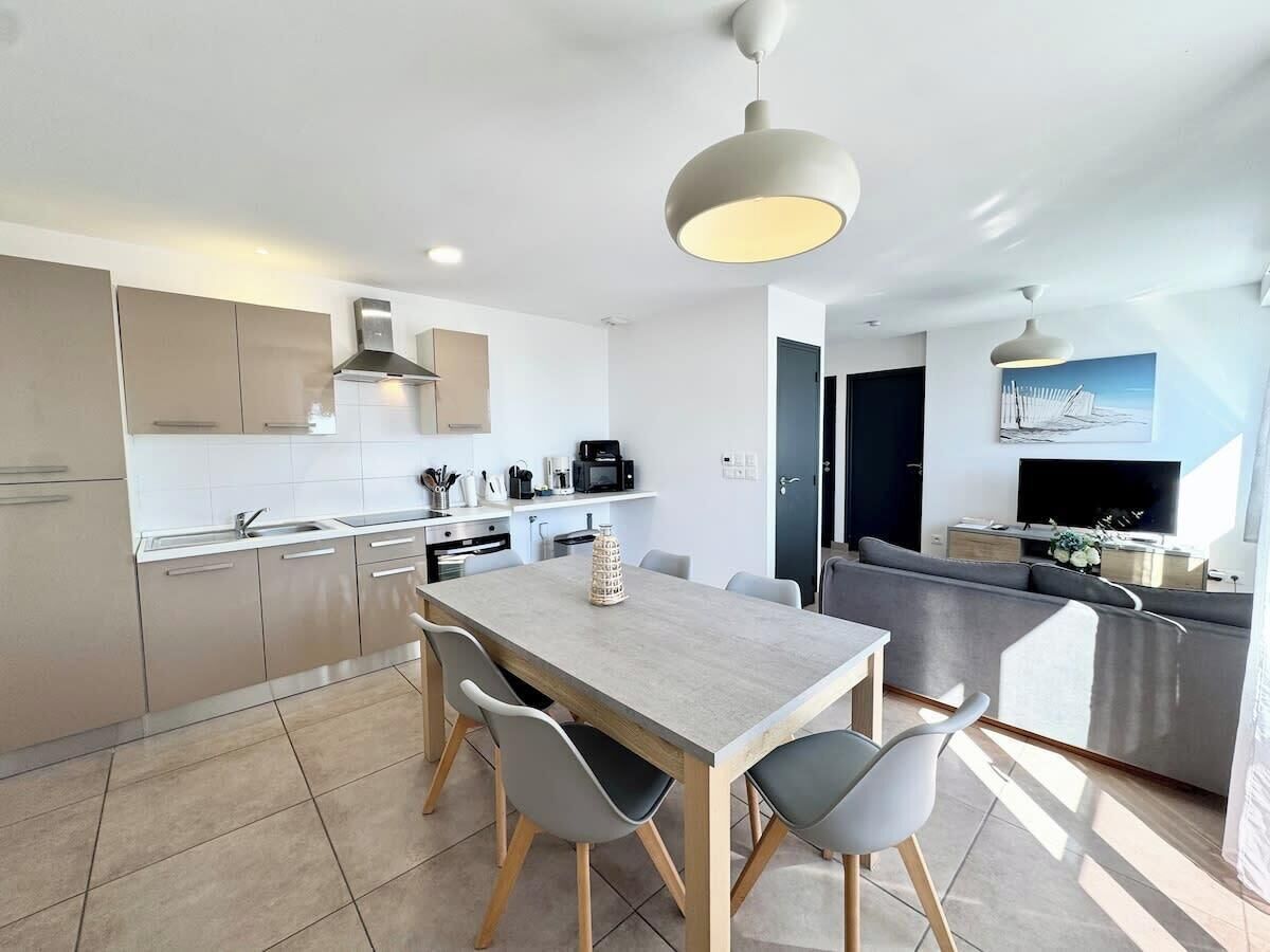 A modern kitchen with a dining area, featuring a large table and chairs, a built-in oven, and a microwave.