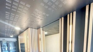 A modern hallway with a patterned ceiling, a wooden slatted wall, and a tiled floor. - T2 contemporain - Balcon - Vue mer panoramique (Guidel)