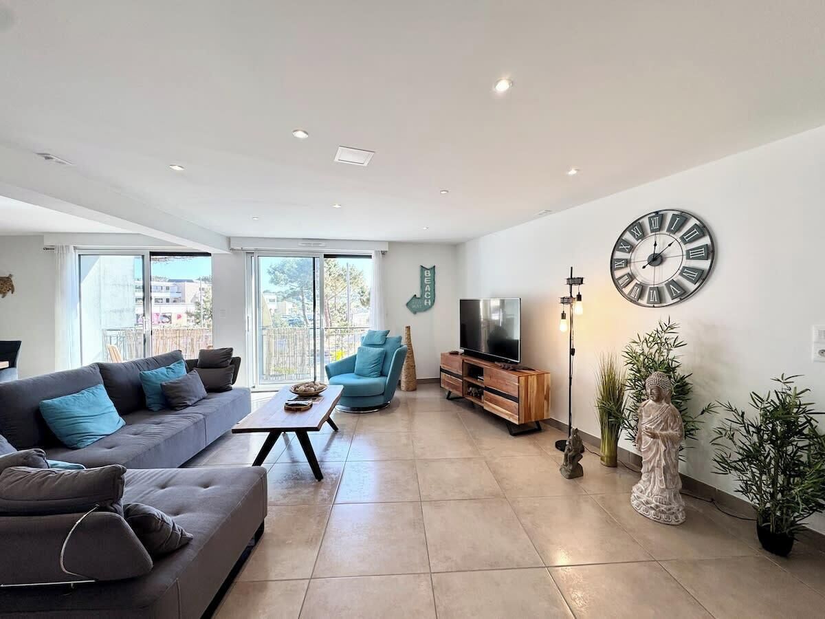 Ein modernes Wohnzimmer mit Sofa, Sessel, Fernseher und Dekorationselementen.