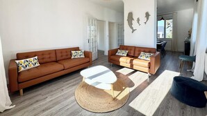 Un vaste espace de vie comprenant deux canapés en cuir marron, une table basse blanche et un tapis tissé.