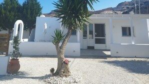 A white building with a gravel driveway, a palm tree, and a potted plant. - Nel cuore di Milos (Milos)