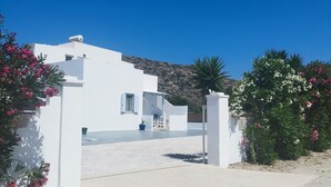 A white building with a driveway and a mountain in the background. - Nel cuore di Milos (Milos)