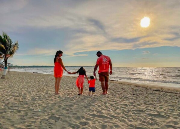A family walking on a sandy beach with the ocean in the background.