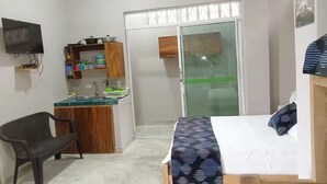 A compact room with a bed, a small kitchenette, a TV, and a sliding glass door leading to another room. - Family Studio Apartment Near the Sea - Coveñas (Coveñas)