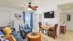 Uma sala de estar com sofá, poltronas, mesa de jantar e ventilador de teto.