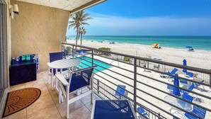 Varanda com vista para a piscina, cadeiras brancas e uma mesa.