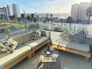 A rooftop seating area with a view of the cityscape, including a Shell gas station and tall buildings. - Vista Herradura (Coquimbo)