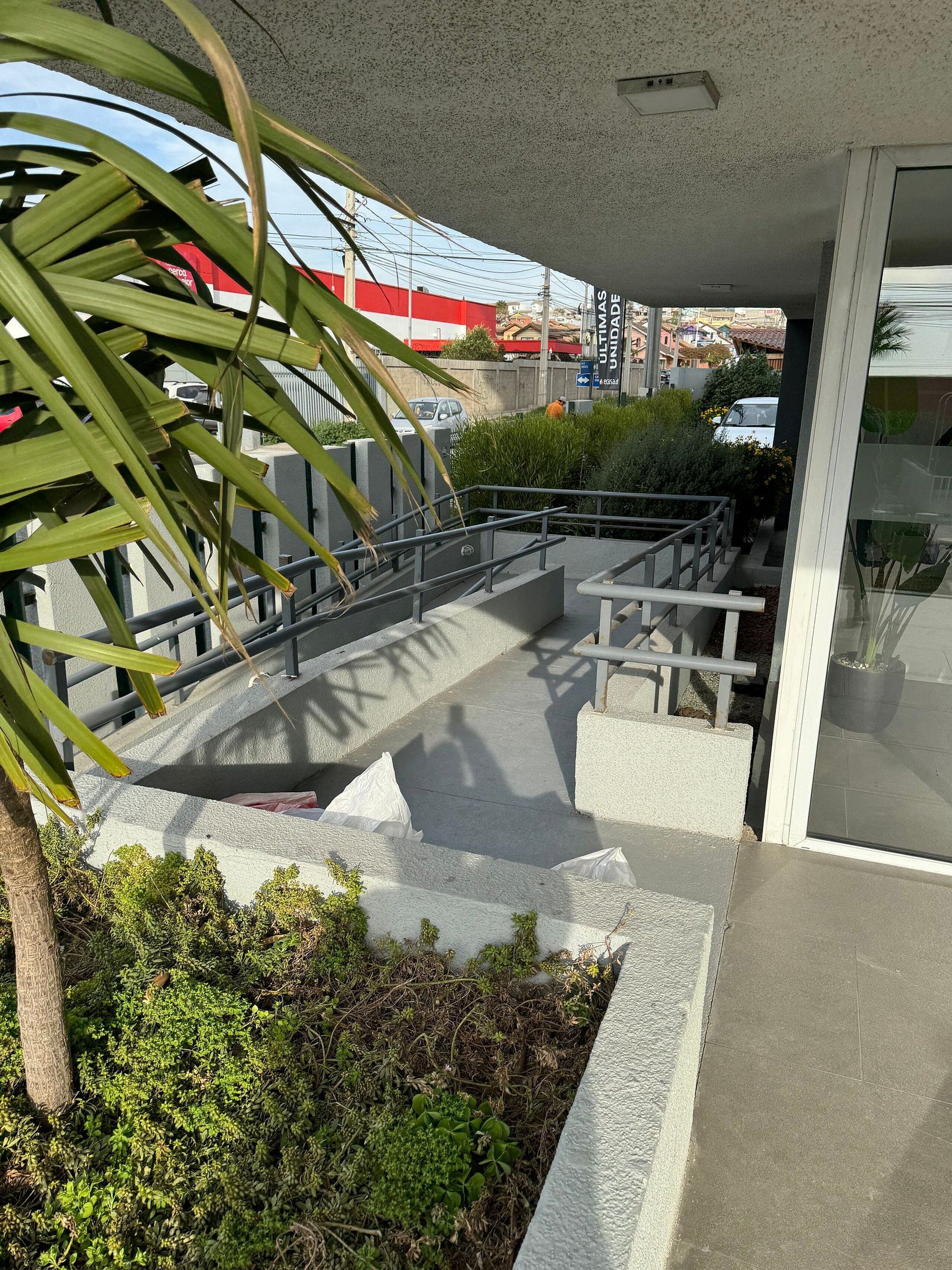 Un espacio al aire libre con escalones de hormigón, barandillas y vegetación.