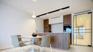 Une cuisine moderne avec un îlot central, des chaises blanches et une table à manger.