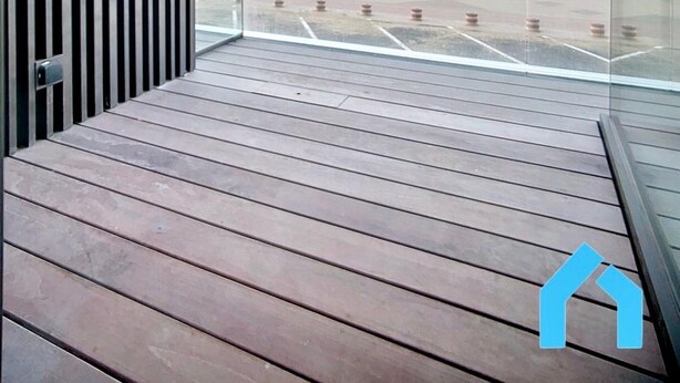 Un balcon donnant sur un parking et sur un paysage lointain.