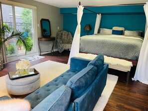 Relax in this serene bedroom with a large bed, a comfortable sofa, and a side table featuring a mirror and lamp.